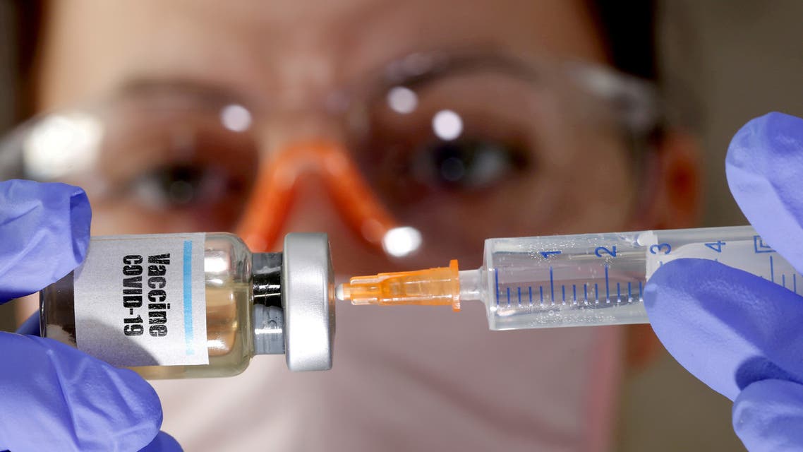 FILE PHOTO: A woman holds a small bottle labeled with a Vaccine COVID-19 sticker and a medical syringe in this illustration taken April 10, 2020. REUTERS/Dado Ruvic//File Photo