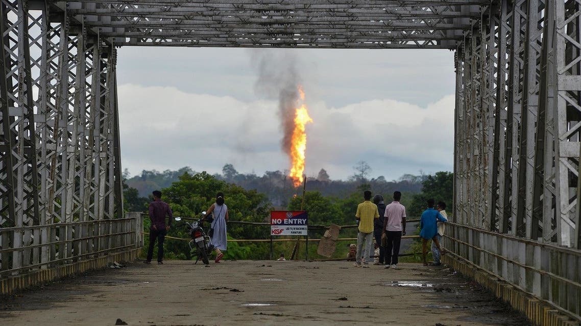 People watch flames and smoke coming out from a well run by state-owned Oil India in Tinsukia, the northeastern state of Assam on June 11, 2020. (Biju Boro/AFP)