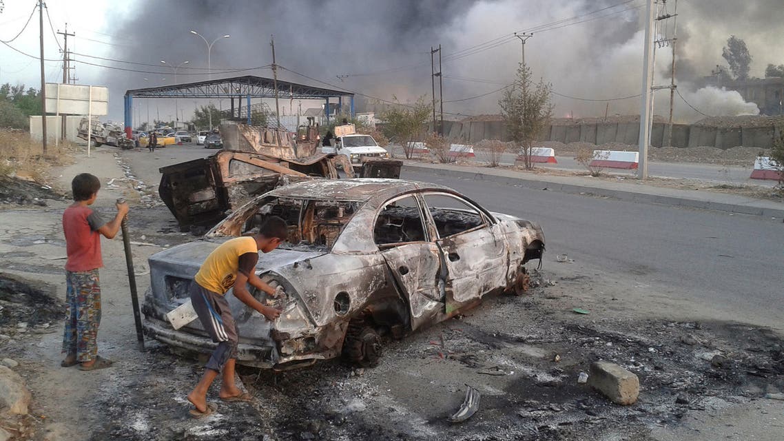 Civilian children stand next to a burnt vehicle during clashes between Iraqi security forces and al Qaeda-linked ISIS in Mosul, Iraq June 10, 2014. (Reuters)