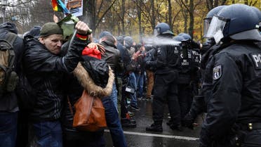 A police officer uses a pepper spray on demonstrators during a protest against the government's coronavirus disease (COVID-19) restrictions, near the Brandenburger Gate in Berlin, November, 18, 2020. (Reuters/Christian Mang)