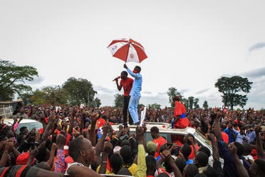 Ugandan musician turned politician Robert Kyagulanyi (C), also known as Bobi Wine, holds an umbrella as he was introduced to supporters during his presidential rally before he got arrested in Luuka, Uganda. (AFP)