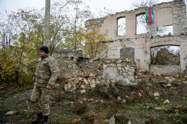 An Azerbaijani soldier walks near a destroyed house on the outskirts of the town of Fuzuli on November 18, 2020. (AFP)