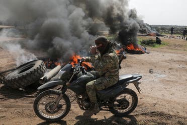 A Turkey-backed Syrian rebel fighter rides on a motorbike near burning tires during a protest against the agreement on joint Russian and Turkish patrols, at M4 highway in Idlib province, Syria, March 15, 2020. (Reuters)