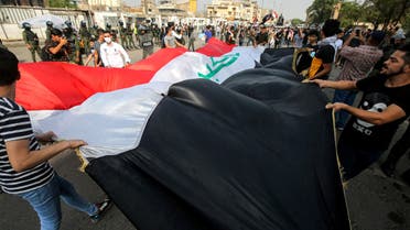 Demonstrators wave together a giant Iraqi national flag during an anti-government protest over corruption and poor services in Tahrir Square in the centre of Iraq's capital Baghdad on November 8, 2020. 