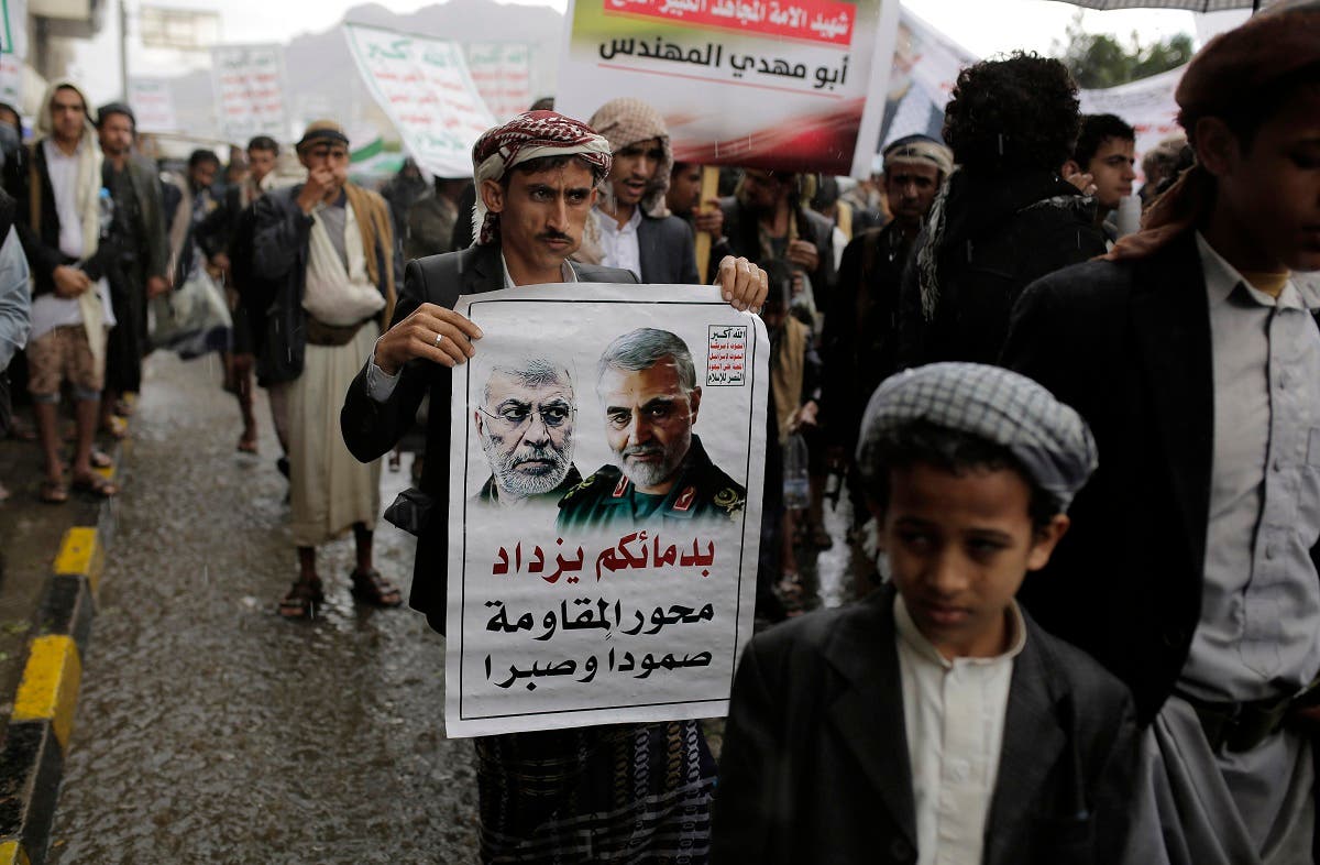 A Yemeni Shia Houthi holds a poster of Iraqi militia commander Abu Mahdi al-Muhandes and Iranian military commander Qassem Soleimani during a protest in Sanaa, Yemen, Jan. 6, 2020. (AP)