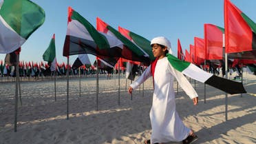 An Emirati boy walks among UAE national flags set up to celebrate the country's Flag Day in Dubai on Nov. 3, 2020. (AP)
