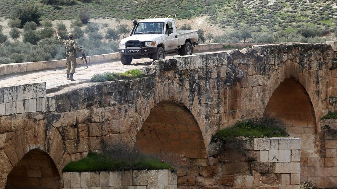 A Turkish-backed Syrian opposition fighter gestures to an incoming pickup truck driving on the Roman bridge in the archaeological site of Cyrrhus, or Nabi Huri, northeast of the Syrian city of Afrin, after they took control of the area from the Kurdish People's Protection Units (YPG) on February 23, 2018.