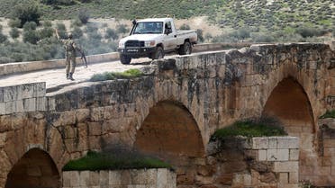 A Turkish-backed Syrian opposition fighter gestures to an incoming pickup truck driving on the Roman bridge in the archaeological site of Cyrrhus, or Nabi Huri, northeast of the Syrian city of Afrin, after they took control of the area from the Kurdish People's Protection Units (YPG) on February 23, 2018. 