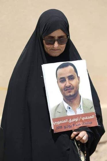 والدة الصحافي المنصوري وهي تحمل صورة ابنها المختطف