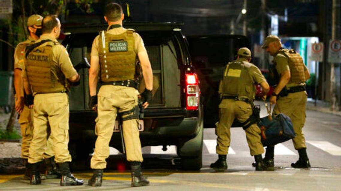 Military police officers carry a bag filled with money left behind by armed bank robbers, in Criciuma, Santa Catarina state, Brazil, Tuesday, Dec. 1, 2020. Dozens of criminals armed with assault rifles invaded the city in southern Brazil overnight and took control of the streets as they assaulted a local bank. (Guilherme Hahn/Futura Press via AP)