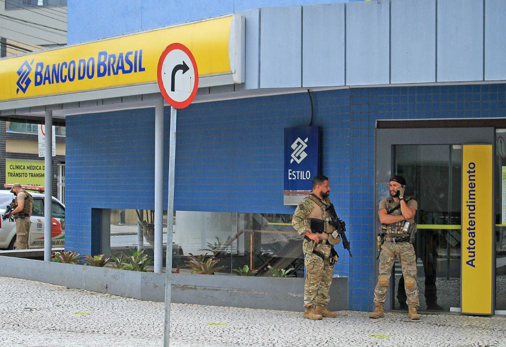 Police officers stand guard outside the bank which robbers struck just after midnight, in Criciuma, Brazil, on December 1, 2020. (Guilherme Haun/AFP)