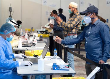 Expatriates, arriving to Kuwait, stand a safe distance apart to give their details to ministry of health officials in a makeshift coronavirus testing centre. (File photo: Reuters)