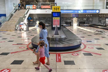 A woman walks with her daugther along a luggage belt as stickers on the ground read Keep your social distance on June 19, 2020 at Antalya International airport in Antalya. (File photo: AFP)