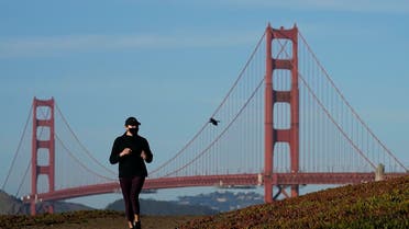 A person wearing a mask runs on a path in front of the Golden Gate Bridge during the coronavirus pandemic in San Francisco. (AP)