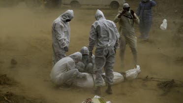 Relatives wearing protective gear tie up the dead body of a victim who died from the COVID-19 coronavirus before the burial at a graveyard in New Delhi on May 10, 2020. 