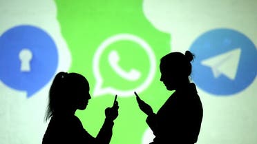 Silhouettes of mobile users are seen next to logos of social media apps Signal, Whatsapp and Telegram projected on a screen in this picture illustration. (Reuters)