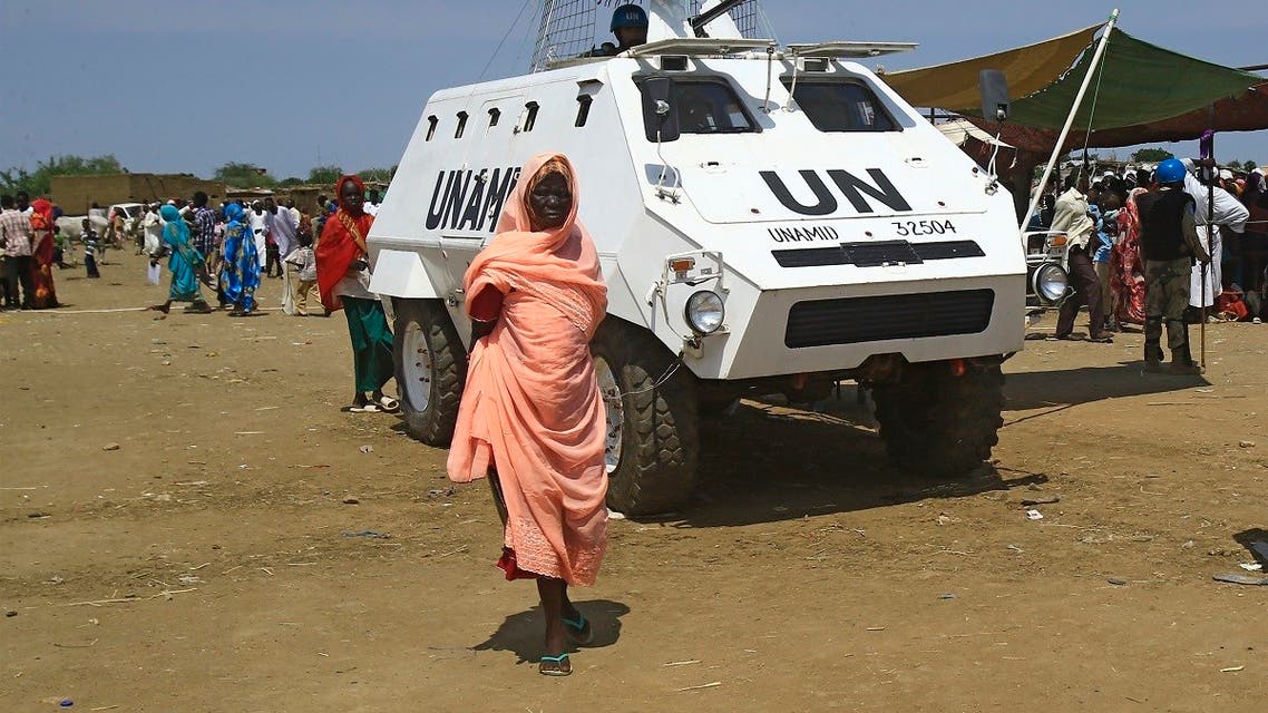 A displaced Sudanese woman walks past a UN-African Union mission to Darfur (UNAMID) vehicle at the Kalma camp for internally displaced people in Darfur’s state capital Niyala on October 9, 2019. (Ashraf Shazly/AFP)