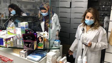 Pharmacist Siham Itani wearing a protective mask looks at her mobile phone inside her pharmacy in Beirut, Lebanon October 6, 2020. (Reuters/Issam Abdallah)