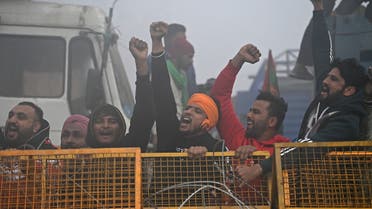 Farmers shout slogans next to a police barricade amid foggy condition during a nationwide general strike to protest against the recent agricultural reforms at the Delhi-Haryana state border in Singhu on December 8, 2020. (AFP)