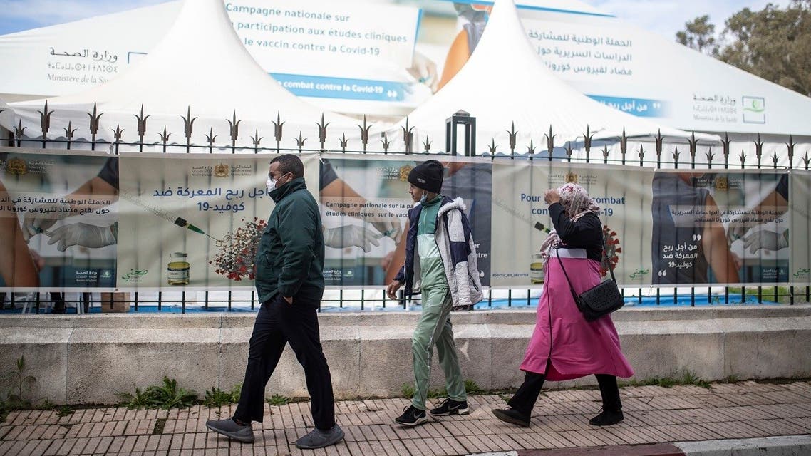 People wearing face masks to prevent the spread of coronavirus walk past a bivouac where clinical trials for covid-19 vaccines are conducted, in Rabat, Morocco, Monday, Dec. 7, 2020. (AP/Mosa'ab Elshamy)