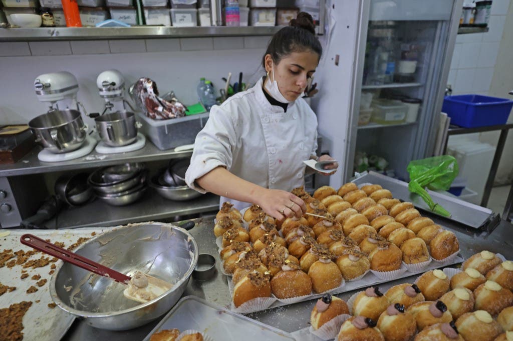 A staff member decorates date-flavoured Abu Dhabi doughnuts created for the Jewish holiday of Hanukkah and in honour to the new diplomatic relations between Israel and the United Arab Emirates, at Kadosh pastry shop in Jerusalem on December 7, 2020. (AFP)