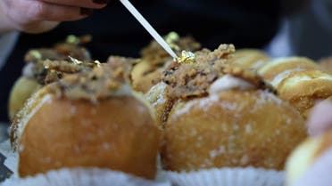 A gold leaf is added atop a date-flavoured Abu Dhabi doughnut at Kadosh pastry shop in Jerusalem on December 7, 2020. (AFP)
