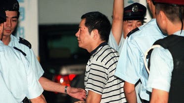 This file photo taken on May 12, 1998 shows Wan Kuok-koi (C), popularly known by his nickname “Broken Tooth,” being led handcuffed into a Macau courthouse by police for charges of involvement in triad activities. (AFP)