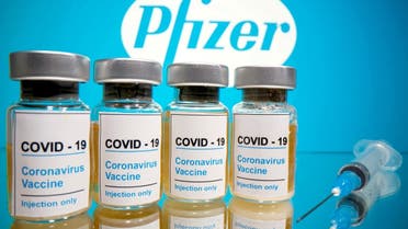 Vials with a sticker reading, “COVID-19 / Coronavirus vaccine / Injection only” and a medical syringe are seen in front of a displayed Pfizer logo in this illustration taken on October 31, 2020. (Reuters)