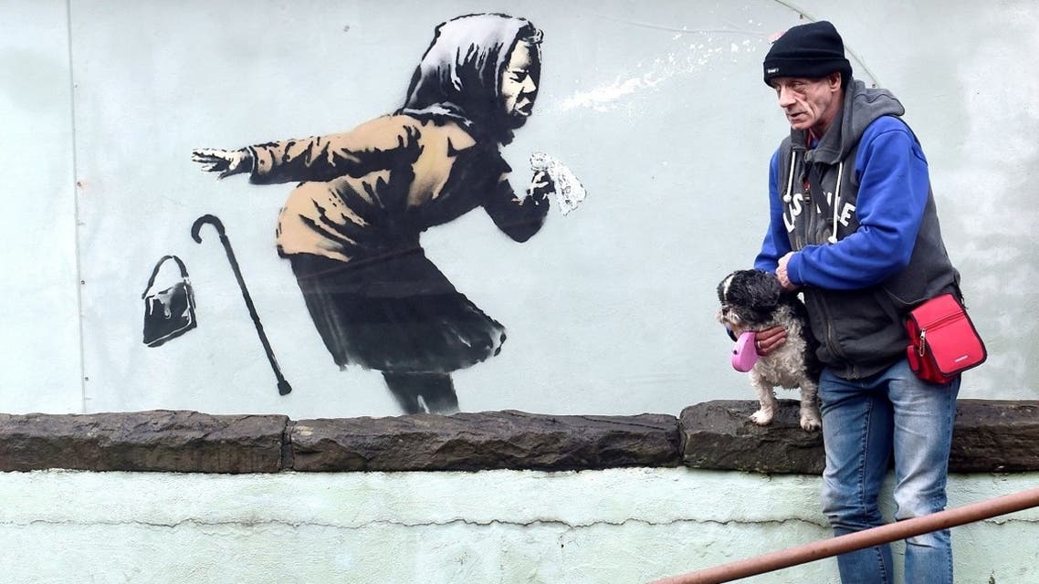 A man stands near a new street artwork entitled ‘Aachoo!!’ by Banksy in Totterdown, Bristol, Britain, on December 11, 2020. (Reuters)