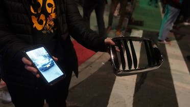 A person holds up parts of a car and shows pictures of it at the location of a car that struck multiple pedestrians during a protest on Third Avenue in the Manhattan. (Reuters)