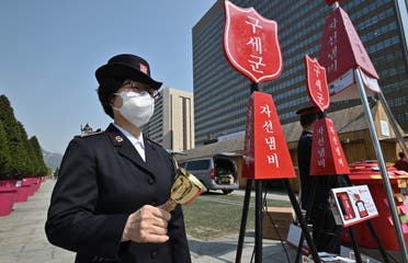 A member of the Salvation Army rings a bell next to a charity pot during a campaign for the donation of face masks in downtown Seoul on March 25, 2020. (AFP)
