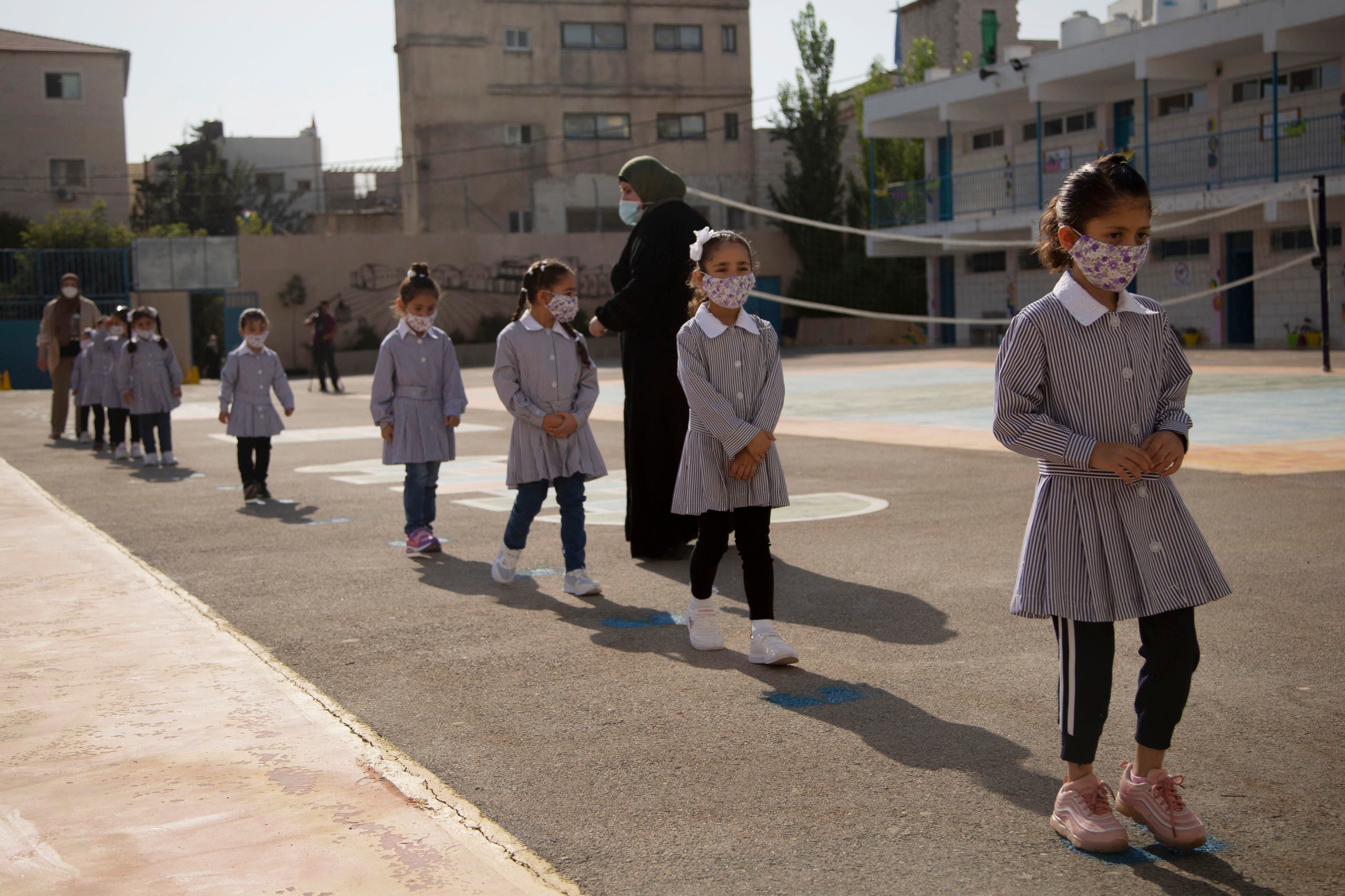 Palestinian elementary school students wearing protective face masks, amid the coronavirus pandemic, enter school on the first day of class at United Nations-run school in the West Bank city of Ramallah, Sunday, September 6, 2020. (The Associated Press/Majdi Mohammed)