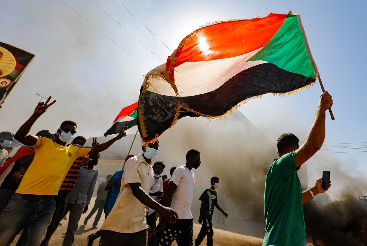 Sudanese youths wave the national flag as they rally in the streets of the capital Khartoum, chanting slogans and burning tires, to mark the second anniversary of the start of a revolt that toppled the previous government, on December 19, 2020. (AFP)