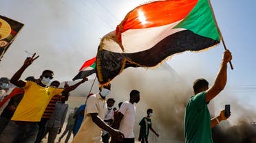 Sudanese youths wave the national flag as they rally in the streets of the capital Khartoum, chanting slogans and burning tires, to mark the second anniversary of the start of a revolt that toppled the previous government, on December 19, 2020. (AFP)