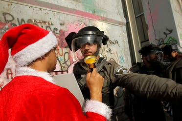 فلسطيني يرتدي ملابس سانتا كلوز مواجها جنديا إسرائيليا (أرشيفية- فرانس برس)