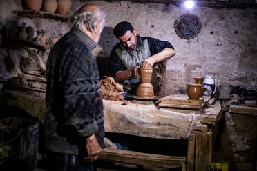 Syrian-Armenian potter Misak Antranik Petros watches his son Anto moulding a clay vase at his workshop located inside an ancient mud-brick house near the city of Qamishli in Syria's northeastern Hasakeh province, on December 19, 2020. (AFP)