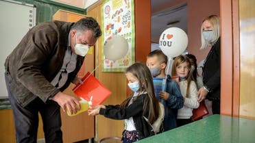 Macedonian school children wearing protective masks to prevent the spread of the novel coronavirus (covid-19) have their hands desinfescted on the first day of the new school year in Skopje on October 1, 2020. (AFP)