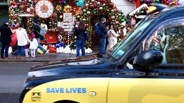 A taxi displaying a “Save Lives” sign passes as people enjoy the Christmas decorations outside The Ivy Chelsea Garden, as the British government imposes a stricter tiered set of restrictions amid the coronavirus pandemic, in London, Britain, on December 20, 2020. (Reuters)