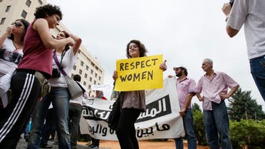 A female activist holding a placard stands amongst men during a protest against family violence near the parliament and government palace in Beirut May 29, 2011. (File photo: Reuters)