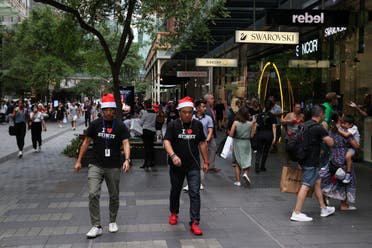 People wearing Santa hats walk through a shopping plaza decorated for the holidays in the city centre of Sydney, Australia, December 17, 2020. (Reuters/Loren Elliott)