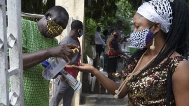 A woman wearing face mask sanitise her hands outside the St. Agnes Catholic Church, Maryland in Lagos, Nigeria. (AFP)