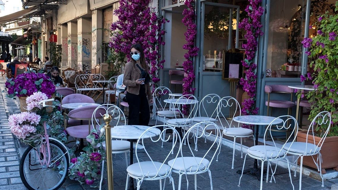 A woman wearing a face mask to prevent the spread of COVID-19 stands at a cafe in central Athens. (AP)