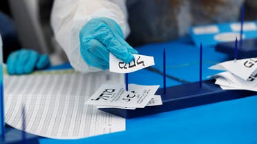 An Israeli election monitor wearing protective gear counts a ballot for the Likud party, headed by Israeli Prime Minister Benjamin Netanyahu, as votes cast by Israelis in home-quarantine over coronavirus concerns following Israel's national election are tallied, in Shoham, Israel March 4, 2020. (Reuters)