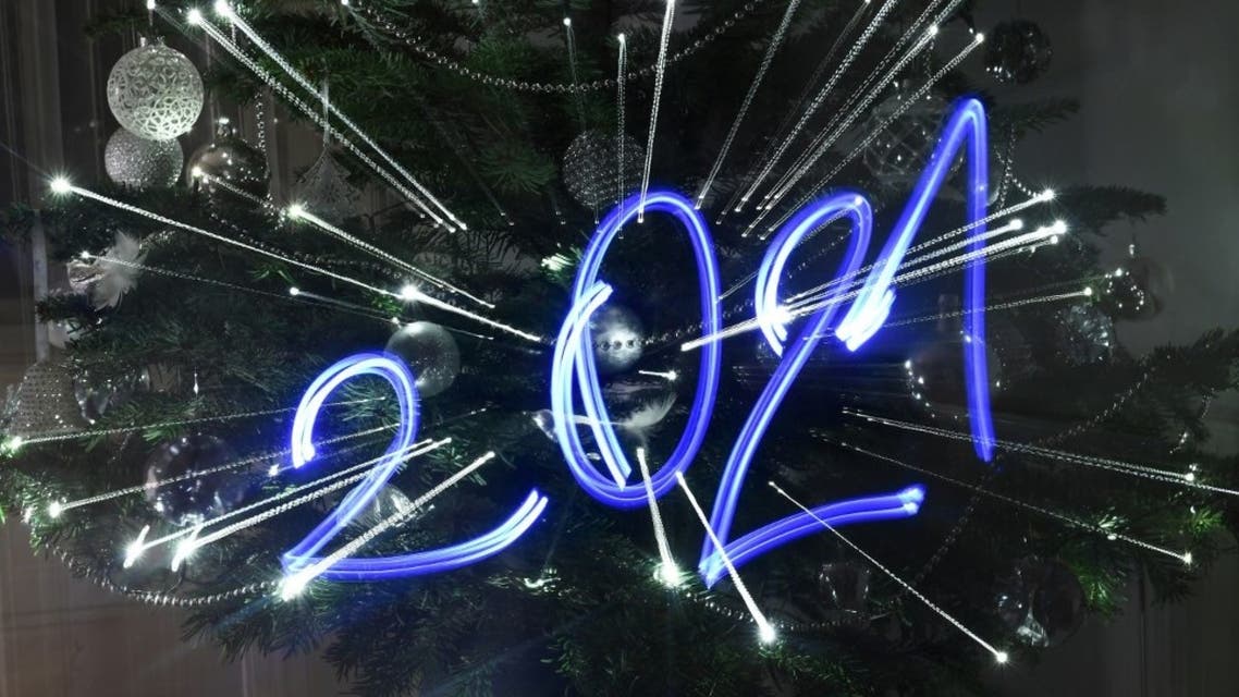 An illustration taken on December 30, 2020 in Budapest shows the numbers of the year 2021 painted with light in front of an illuminated Christmas tree. (AFP)