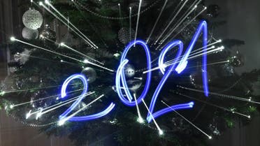 An illustration taken on December 30, 2020 in Budapest shows the numbers of the year 2021 painted with light in front of an illuminated Christmas tree. (AFP)