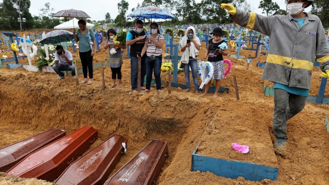 In this file photo taken on May 6, 2020 mourners stand besides a mass grave at the Nossa Senhora cemetary in Manaus, Amazon state, Brazil, amid the COVID-19 coronavirus pandemic. (AFP)