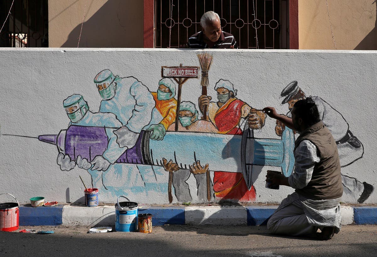 A man applies finishing touches to graffiti representing a vaccine, amidst the spread of coronavirus disease (COVID-19) in Kolkata, India. (File photo: Reuters)