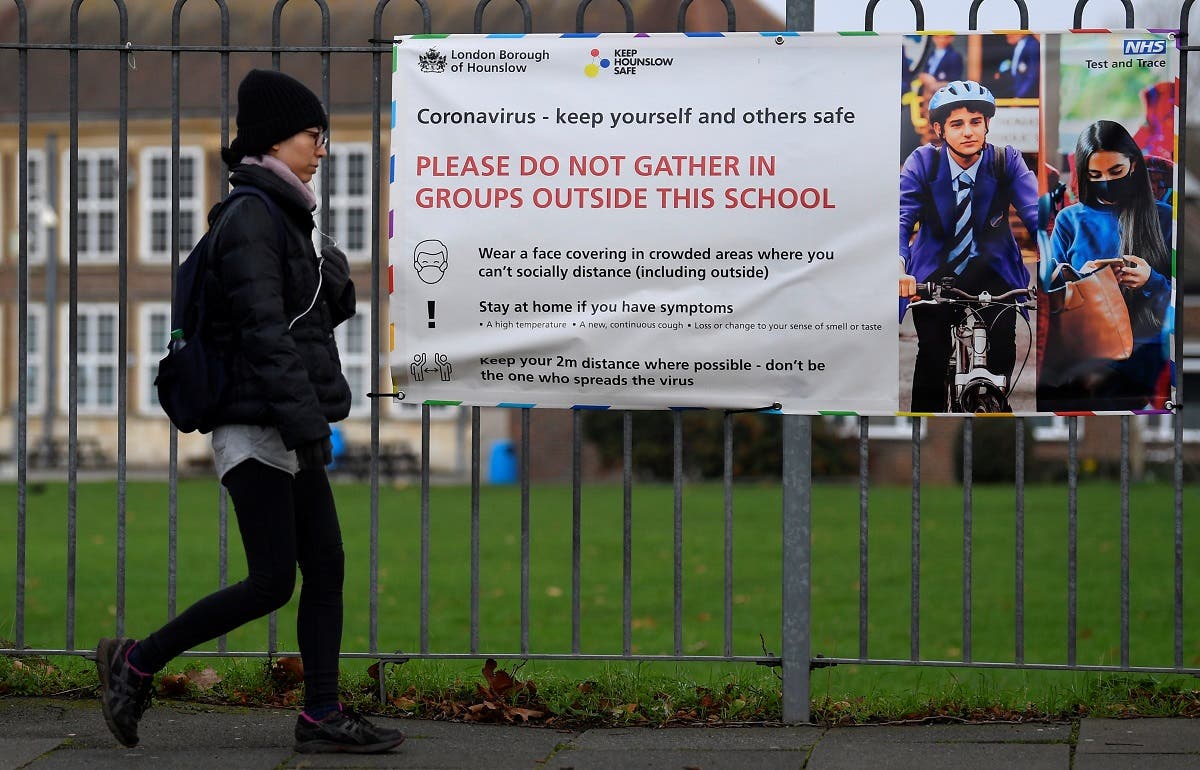 A woman walks past a social distancing health message outside of a secondary school in London. (Reuters)