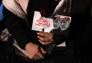 An Iraqi woman carries a portrait of Abu Mahdi al-Mohandes and Qasem Soleimani at Baghdad Airport. (AFP)