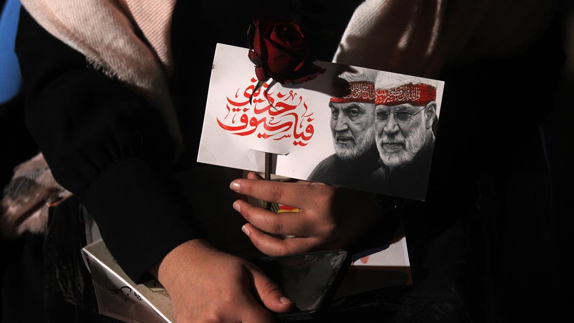 An Iraqi woman carries a portrait of Abu Mahdi al-Muhandis and Qasem Soleimani at Baghdad Airport. (AFP)